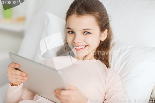 Image of happy girl lying in bed with tablet pc at home