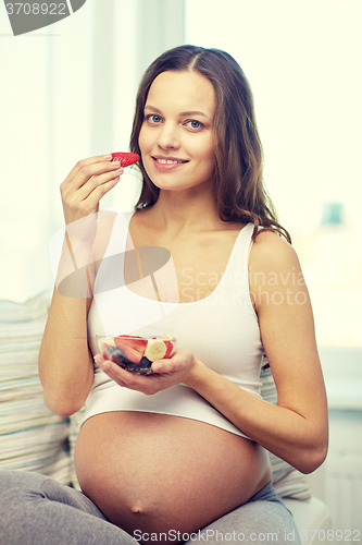Image of happy pregnant woman eating fruits at home