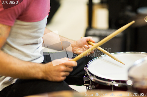 Image of close up of musician with drumsticks playing drums
