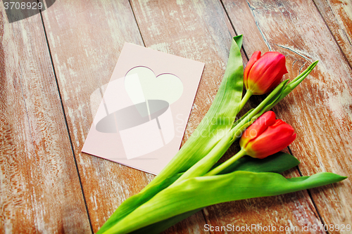 Image of close up of tulips and greeting card with heart