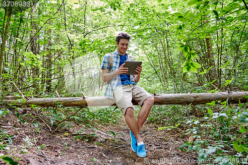 Image of happy man with backpack and tablet pc in woods