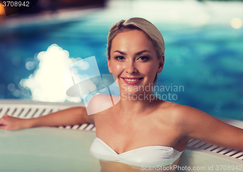 Image of happy woman sitting in jacuzzi at poolside