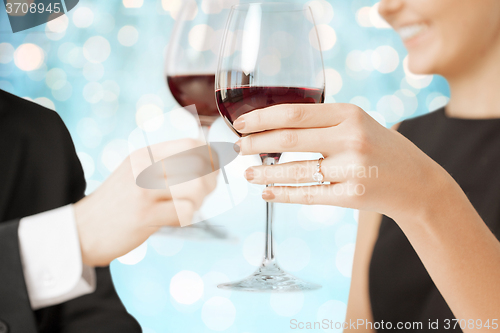 Image of happy engaged couple clinking wine glasses