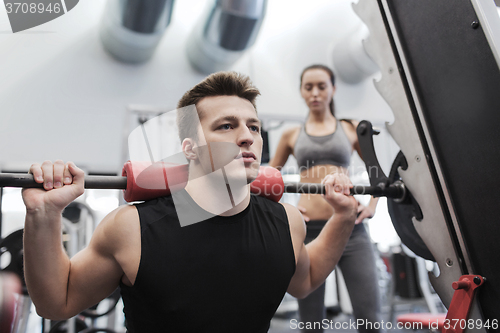 Image of man and woman with barbell flexing muscles in gym