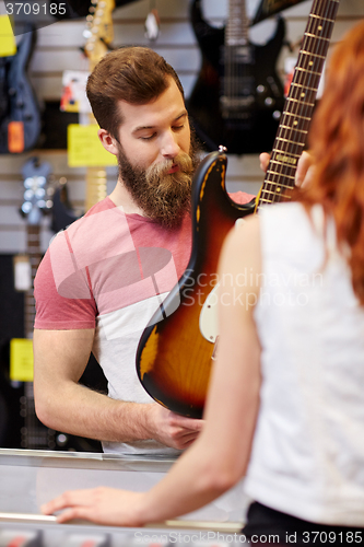 Image of assistant showing customer guitar at music store