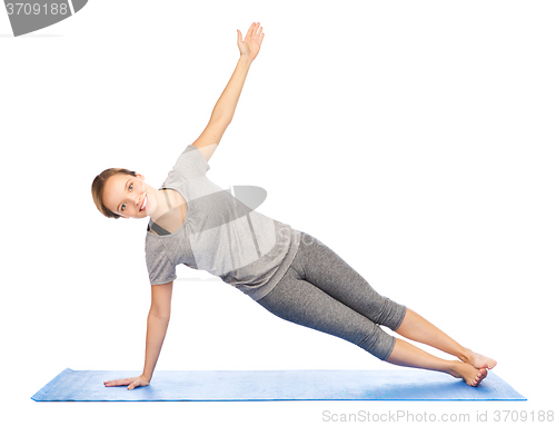 Image of woman making yoga in side plank pose on mat