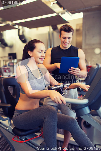 Image of happy woman with trainer on exercise bike in gym