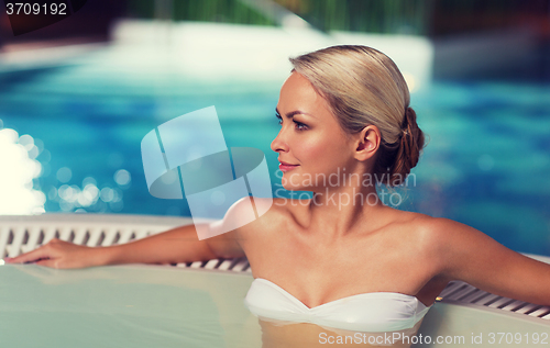 Image of happy woman sitting in jacuzzi at poolside