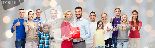 Image of happy people with red sale sign showing thumbs up