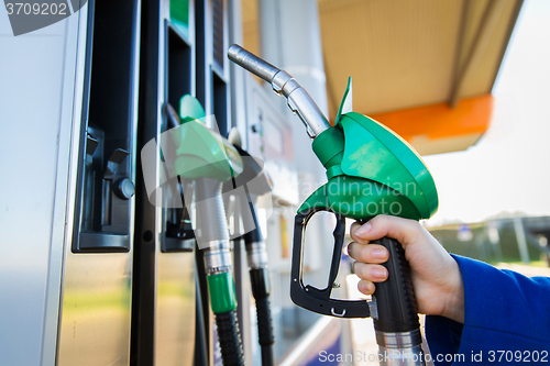 Image of close up of hand holding hose at gas station