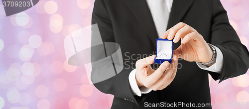 Image of close up of man with gift box and engagement ring