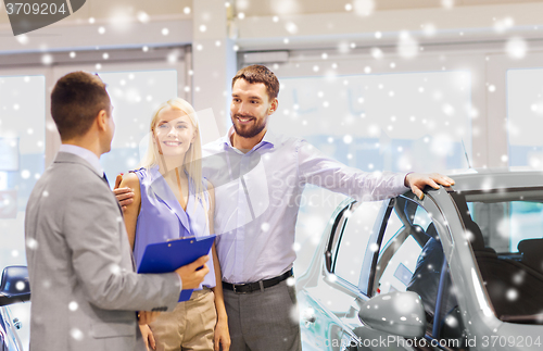 Image of happy couple with car dealer in auto show or salon