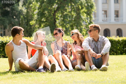 Image of group of smiling friends outdoors sitting on grass