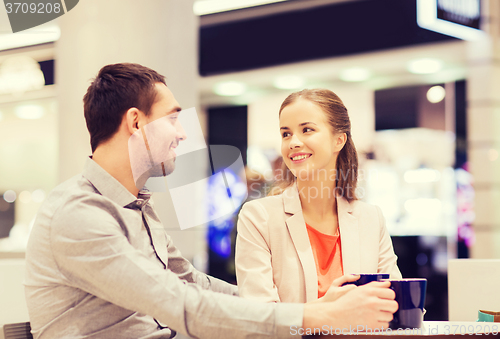 Image of happy couple with shopping bags drinking coffee