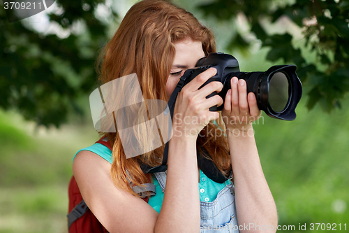 Image of young woman with backpack and camera outdoors