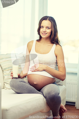 Image of happy pregnant woman drinking milk at home