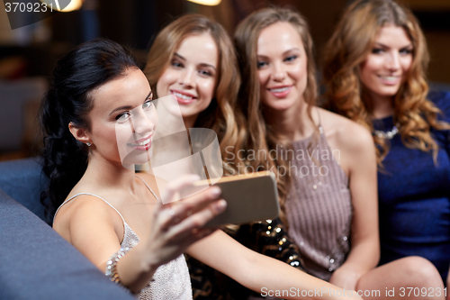 Image of women with smartphone taking selfie at night club