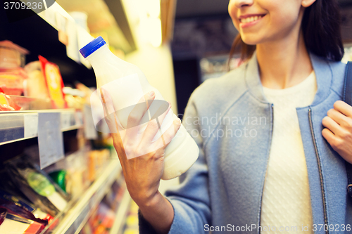 Image of happy woman holding milk bottle in market