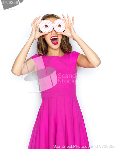 Image of happy woman or teen girl having fun with donuts