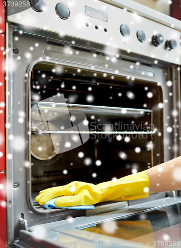 Image of close up of woman cleaning oven at home kitchen