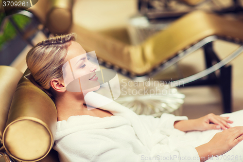 Image of beautiful young woman sitting in bath robe at spa