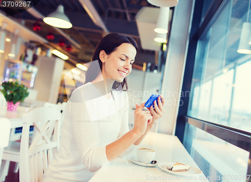 Image of smiling woman with smartphone and coffee at cafe
