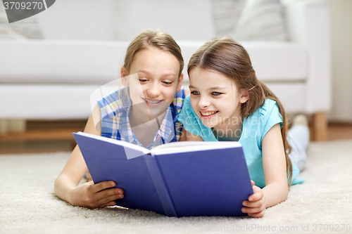 Image of two happy girls reading book at home