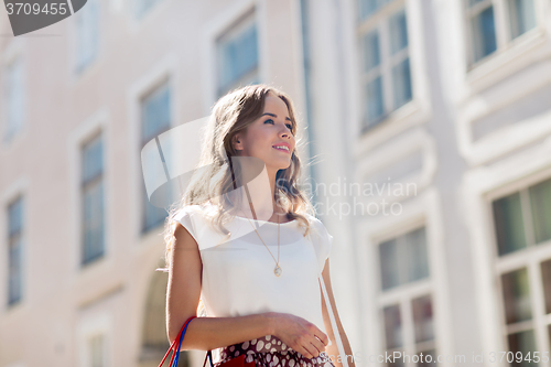 Image of happy woman with shopping bags walking in city 