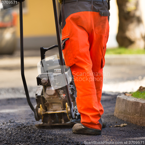 Image of Asphalt surfacing manual labor.