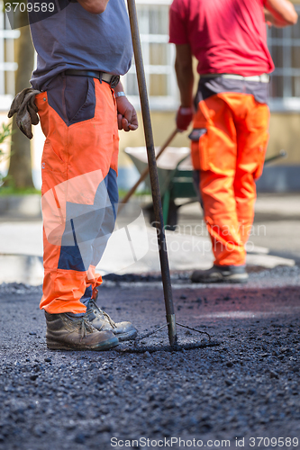 Image of Asphalt surfacing manual labor.