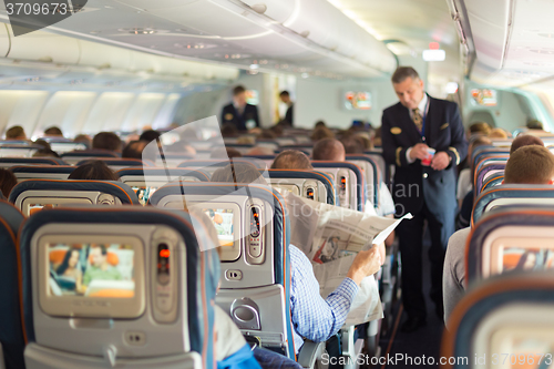 Image of Steward and passengers on commercial airplane.