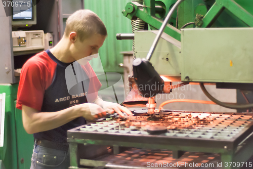 Image of Worker operates computerized metalworking machine