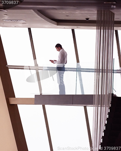 Image of young successful business man in penthouse apartment working on 