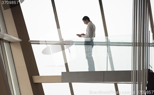 Image of young successful business man in penthouse apartment working on 