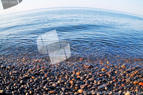 Image of stone in the coastline sunrise and light ocean white sky