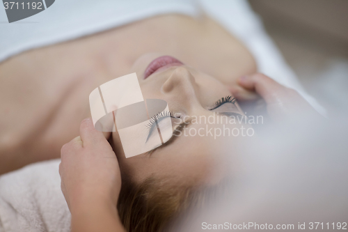 Image of woman getting face and head  massage in spa salon