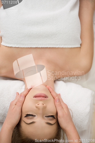 Image of woman getting face and head  massage in spa salon