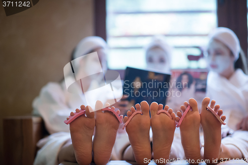 Image of bachelorette party in spa, girls with face mask reading magazine