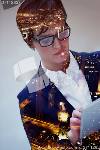 Image of double exposure of business woman working on tablet computer