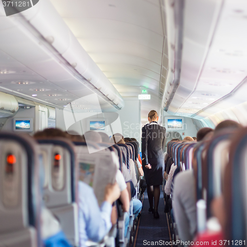 Image of Stewardess and passengers on commercial airplane.