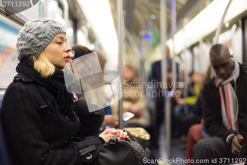 Image of Woman napping on subway full of people.