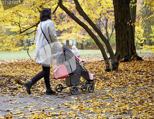 Image of woman with pram in autumnal park