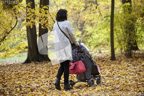 Image of woman with pram in autumnal park