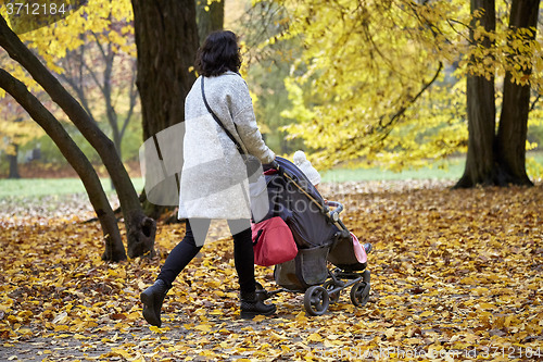 Image of woman with pram in autumnal park