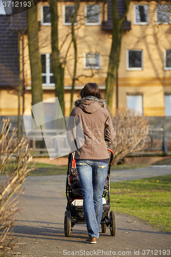 Image of woman with pram in autumnal park