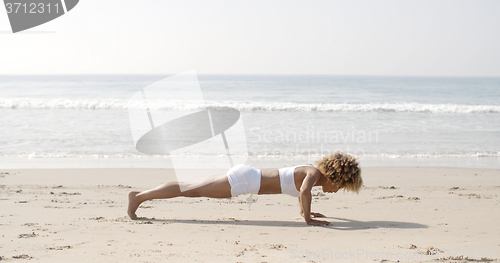 Image of Young Woman Doing Push-Ups On Beach