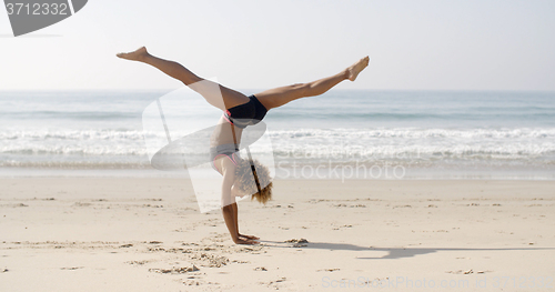 Image of Young Woman Doing Cartwheel On The Beach