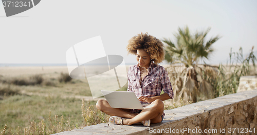 Image of Woman With Laptop Sitting On Stone Wall