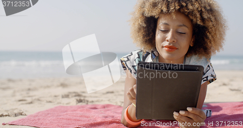 Image of Woman Uses A Tablet On The Beach