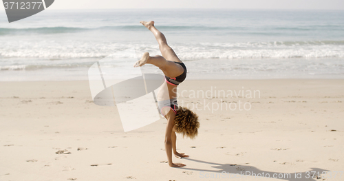 Image of Young Woman Doing Cartwheel On Beach